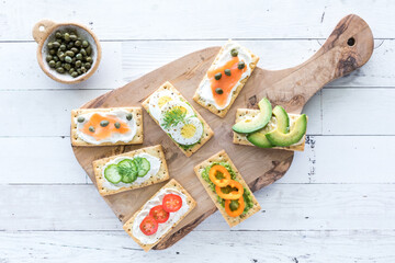 A wooden board with everything crackers and various fresh toppings.