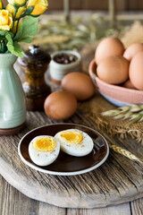 A sliced boiled egg on a small plate with other whole eggs in behind. 