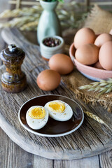 Close up of a sliced boiled egg on a small plate with other raw eggs in behind.