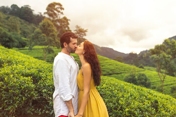 Romantic couple of travelers in love kissing against nature background tea plantations landscape....