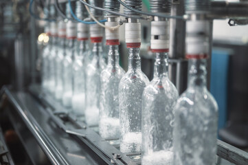 Equipment pours vodka into glass bottles on production line