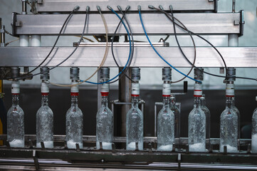 Filling glass bottles with vodka drink on production line