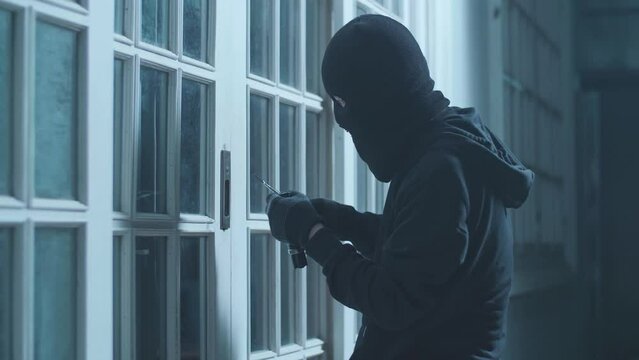 Thief Man Holding Flashlight Trying To Open The Door Of Someone'S House 
