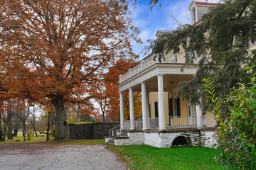 Large front porch of old house, with oak tree in fall colors