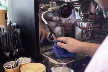 Hand of barista cleaning steam wand coffee machine in daily use by streaming pressure.