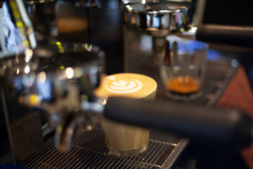 Latte coffee with latte art is on top of the dry box of the espresso coffee machine. Espresso in a...