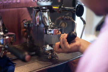 The barista prepares a portafilter containing tampered coffee grounds to be inserted into the ground head of the coffee machine. The process of making espresso coffee.