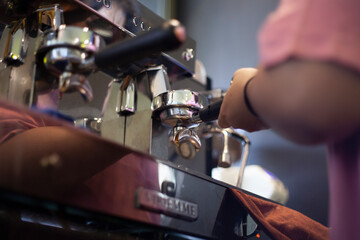 Barista attaching portafilter to the apparatus coffee to make coffee for customers in the cafe. Coffee Preparation Service Concept.