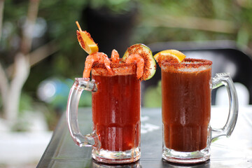 Micheladas served on an outdoor table, it is a Mexican alcoholic drink that is prepared by mixing...