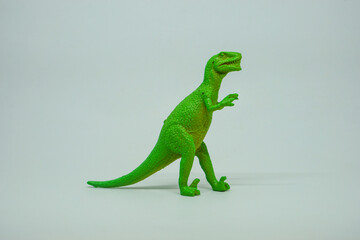 Side view of plastic green Tyrannosaurus rex dinosaur plastic toy for kids, isolated on a studio lighting background © LADALIDI