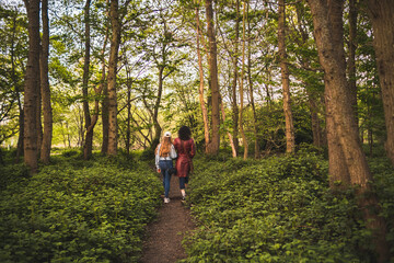 Fototapeta premium Woman and her teenage daughter walking on footpath in park 