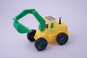 Hight angle view of excavator model toy, green and yellow color, with studio lighting background