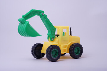 Side view of excavator model toy, green and yellow color, with studio lighting background
