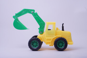 Fototapeta na wymiar Side view of excavator model toy, green and yellow color, with studio lighting background