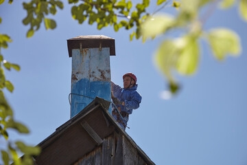 An employee of the Industrial Mountaineering Service paints the chimney on the roof with a spray...