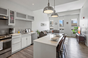beautiful kitchen in new luxury home with island, pendant lights, hardwood floors, and stainless steel appliances