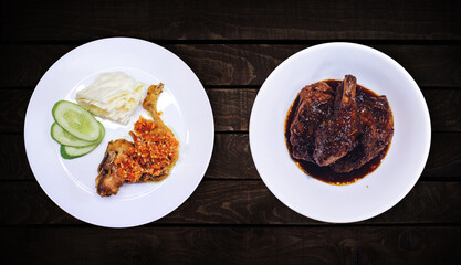 Side dish, sweet spicy chicken dish is on white plate on dark wooden background, top view.