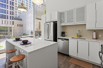 beautiful kitchen in new luxury home with island, pendant lights, hardwood floors, and stainless steel appliances
