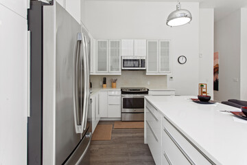 beautiful kitchen in new luxury home with island, pendant lights, hardwood floors, and stainless steel appliances