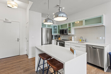 beautiful kitchen in new luxury home with island, pendant lights, hardwood floors, and stainless steel appliances
