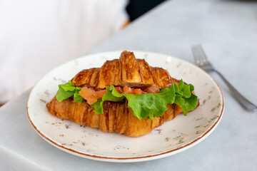 Delicious and healthy breakfast croissant with salmon lettuce and cream cheese on a plate