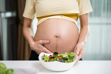 Close up of Asian woman pregnant standing and holding mix slad bowl. 