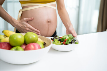 Close up of Asian woman pregnant standing and holding mix slad bowl. 