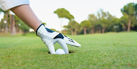 White golf glove and ball in the hole