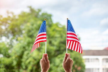 hand holding United States of America flag on green background. USA holiday of Veterans, Memorial, Independence ( Fourth of July) and Labor Day concept