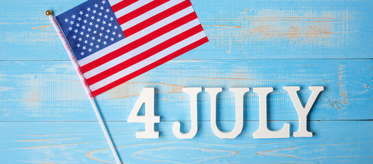 Fourth of July text and United States of America flag on wooden table background. USA holiday of Independence and celebration concepts