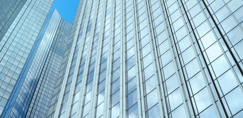 Blue glass wall of modern skyscraper with the clouds reflection on windows. Modern office building...