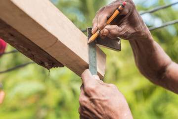 A carpenter marks the excess edge of a wood rafter with a pencil. Using a L-square ruler to make a...