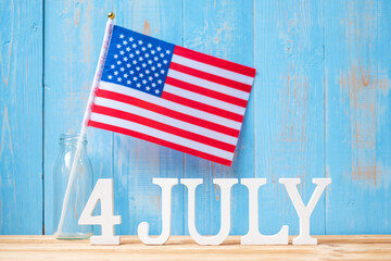 Fourth of July text and United States of America flag on wooden table background. USA holiday of Independence and celebration concepts