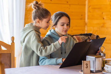Two girls are in a restaurant and choose dishes from the menu