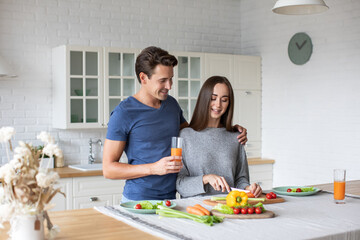 Romantic young couple cooking together in the kitchen having a great time together.