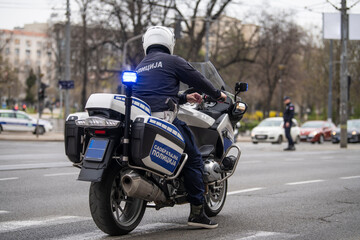 Policeman on motorcycle patrol on the street. Translation: 