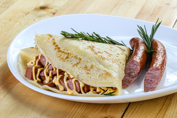Pancake with sliced sausage and mustard