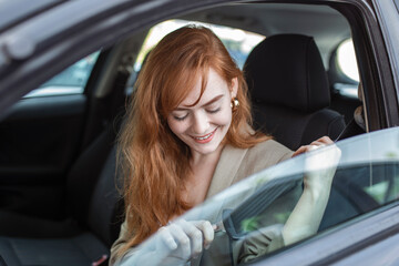 Young woman sitting on car seat and fastening seat belt, car safety concept. Woman fastens a seat belt in the car. Caucasian woman driver fastening car seat belt while sitting behind the wheel car.