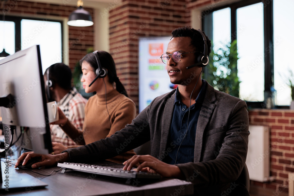 Poster african american helpline employee working at call center reception with multiple monitors. male ope