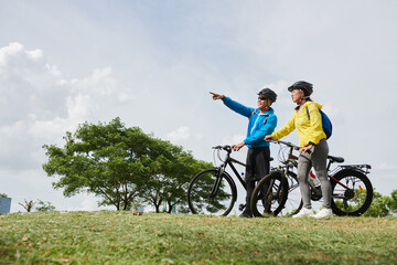 Fototapeta premium Couple on bicycles standing on hill and deciding where to ride