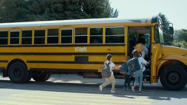 Energetic teen students rushing into school bus. Happy schoolchildren boarding.