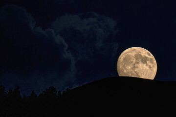 Fototapeta na wymiar beautiful moonrise over the mountains with tree silhouettes on the horizon