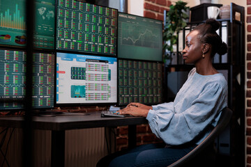 Brokerage agency agent sitting at multi monitor workstation while trading risk free assets....