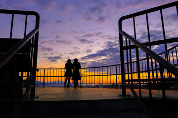 silhouette of a couple walking on the pier