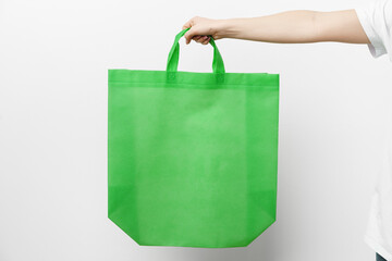 Female hand holding eco or reusable shopping bag against white background