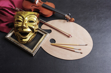 Art attributes. Painting, music, theater. Art palette and brushes, violin and comedy theatrical mask. Dark background. - obrazy, fototapety, plakaty