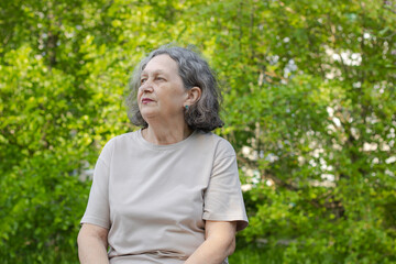 Sad elderly woman reflects on life. Wrinkles on the face, gray hair. Retirement age