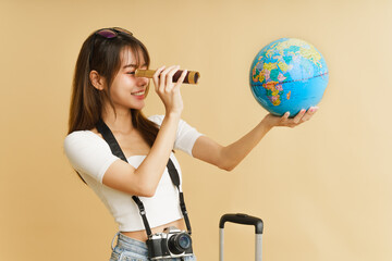 Asian woman traveling concept,  The girl using telescopic to looking to the globe in her hand.