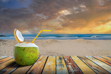 Fresh coconut juice and straw inside on tropical beach in sunset, sunrise sky, Koh Samui, Thailand