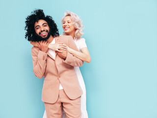 Smiling beautiful woman and her handsome boyfriend. Sexy cheerful multiracial family having tender moments on beige background in studio. Multiethnic models hugging. Embracing each other.Love concept
